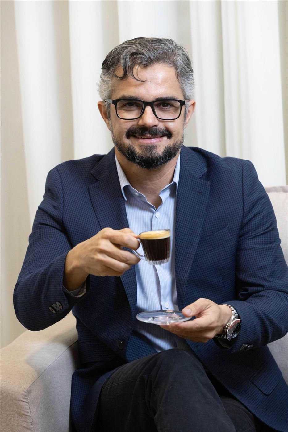 Retrato de Fábio Silva sorrindo, sentado em seu escritório